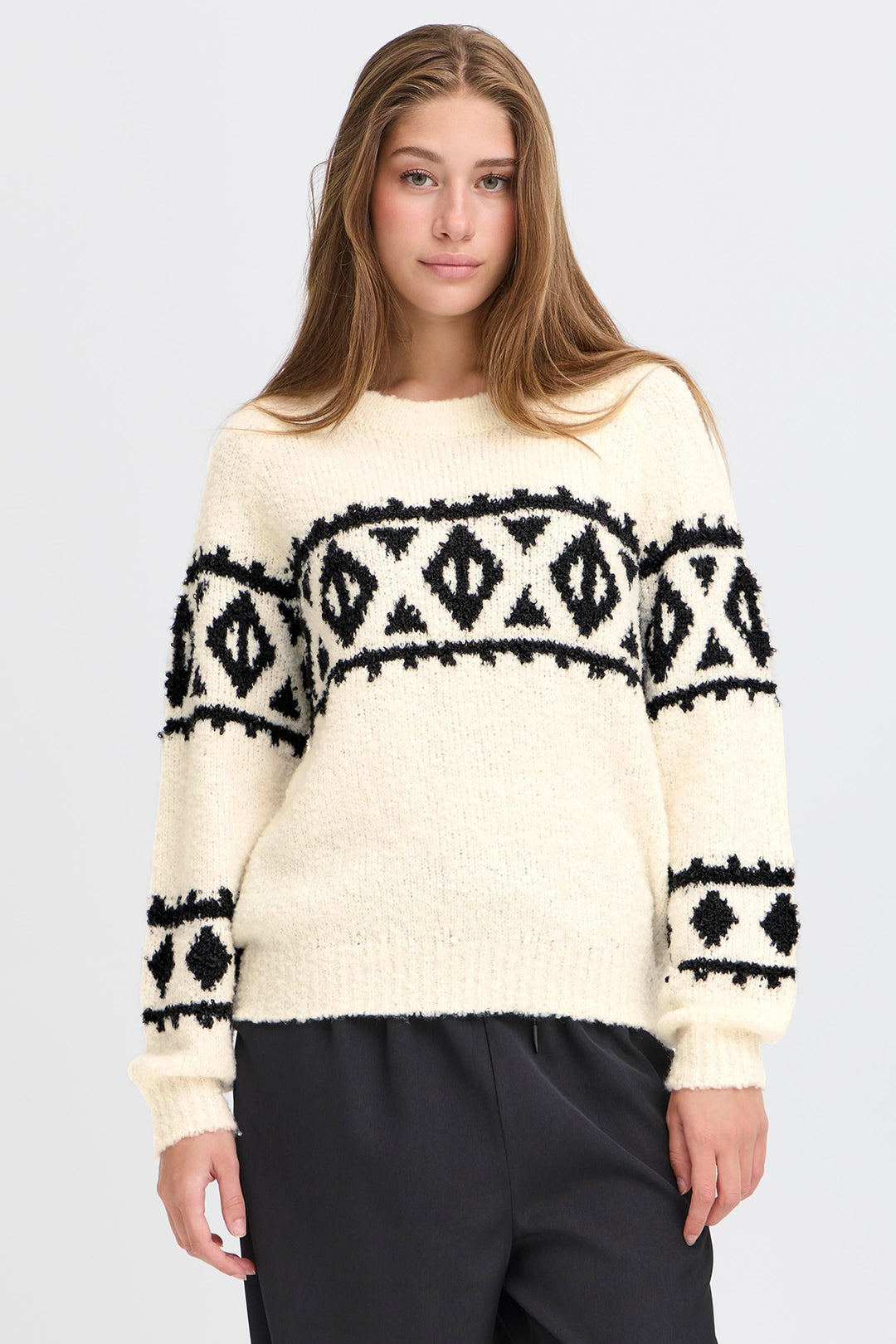 Woman wearing a cream sweater with black pattern on a white background