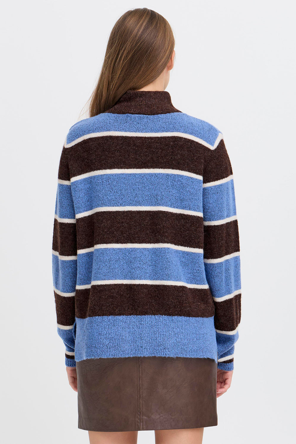 Person wearing a striped sweater with blue, brown, and white colors on a plain background