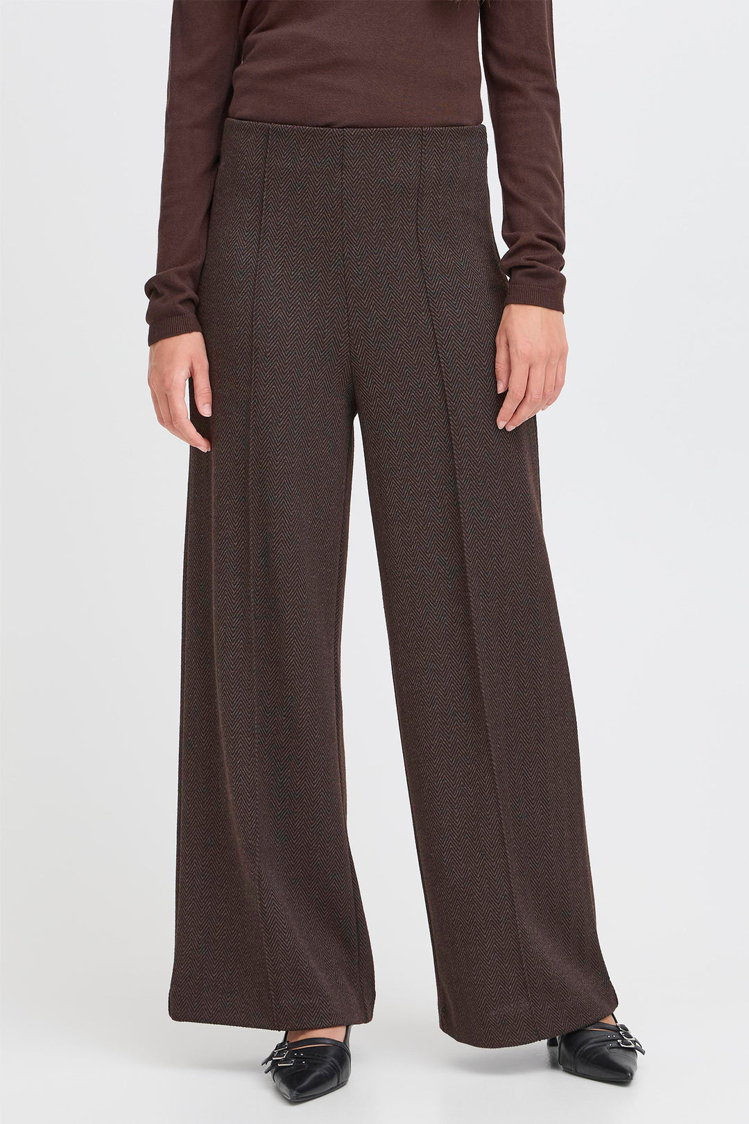 Person wearing brown wide-leg pants and a matching top on a white background