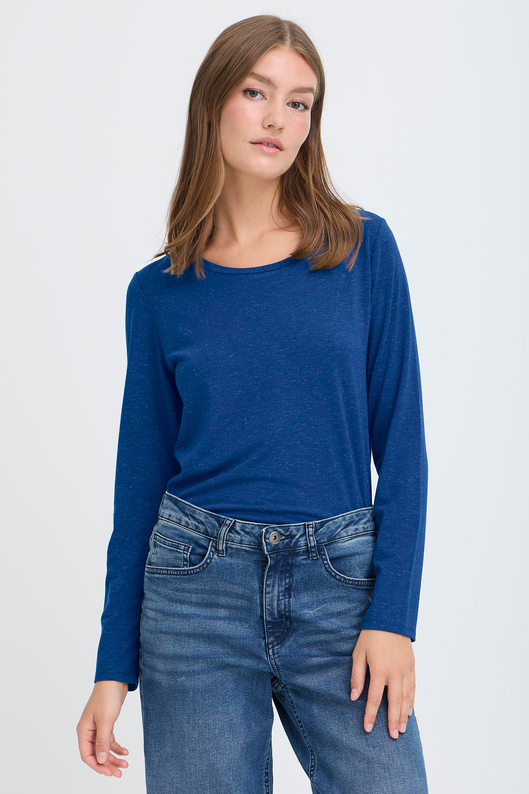 Woman wearing a blue long-sleeve top and jeans on a white background