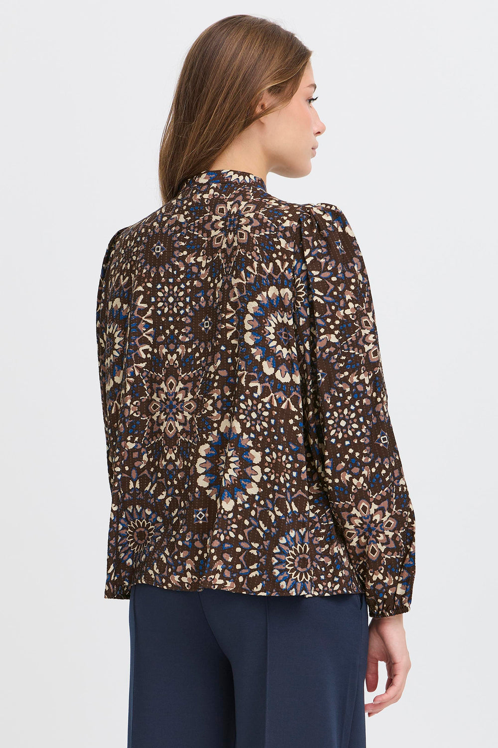 Woman wearing a patterned blouse with long sleeves on a white background