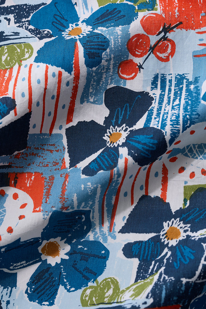 Close-up of a fabric with blue floral and abstract patterns in red, white, and green.