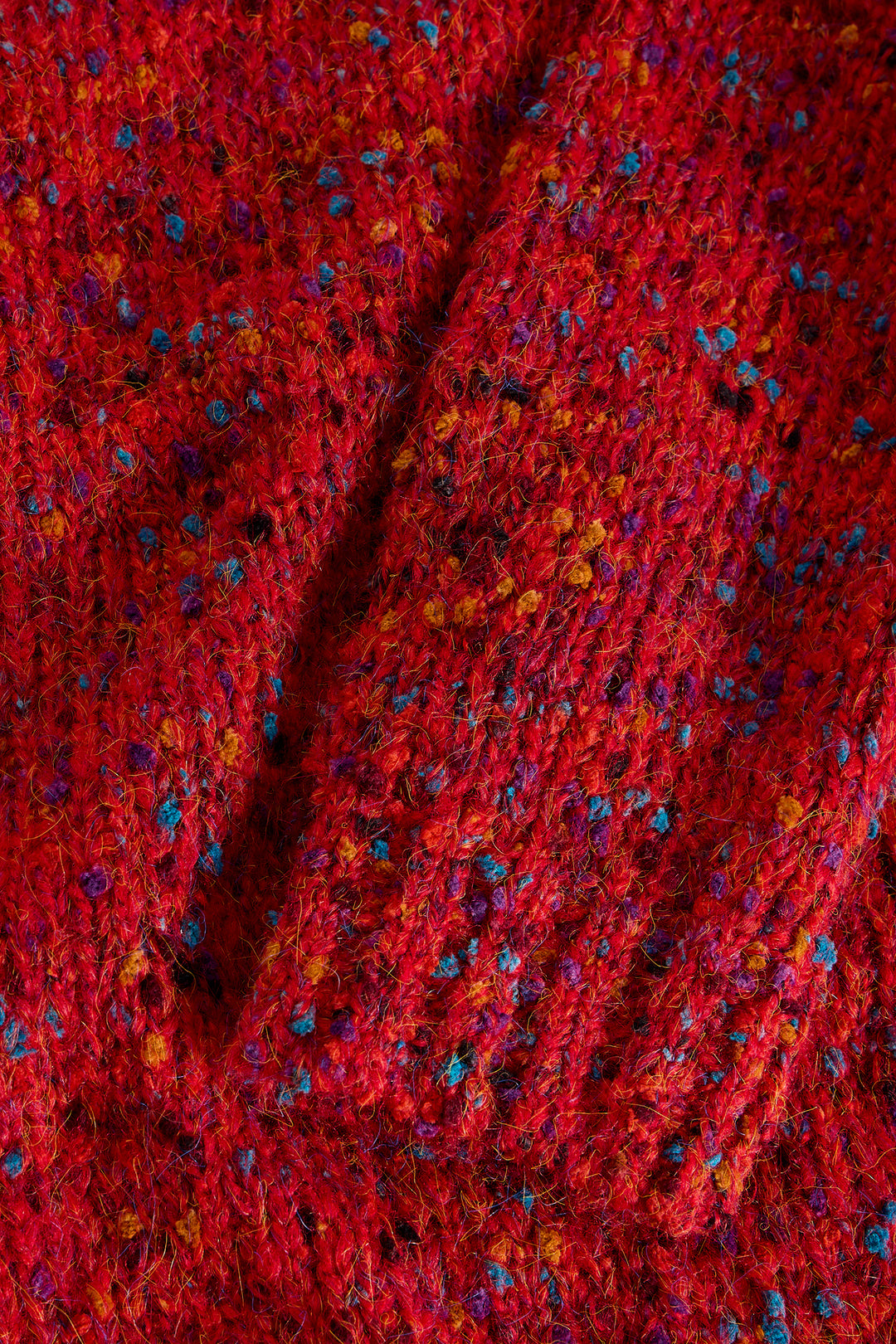Close-up of a red textured fabric with small multicolored specks