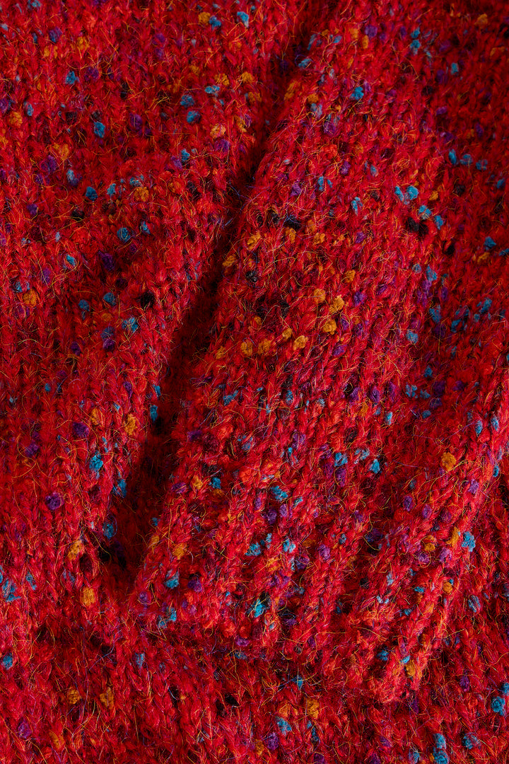 Close-up of a red textured fabric with small multicolored specks