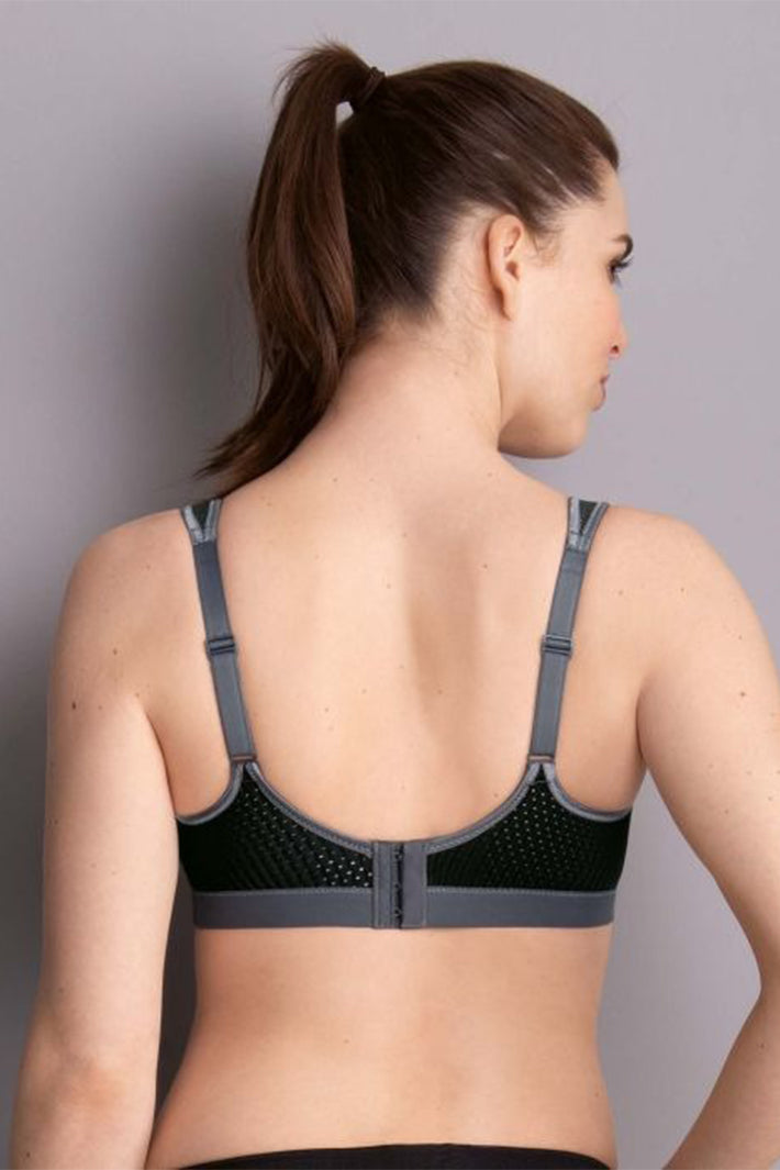Woman wearing a black and gray sports bra against a plain background