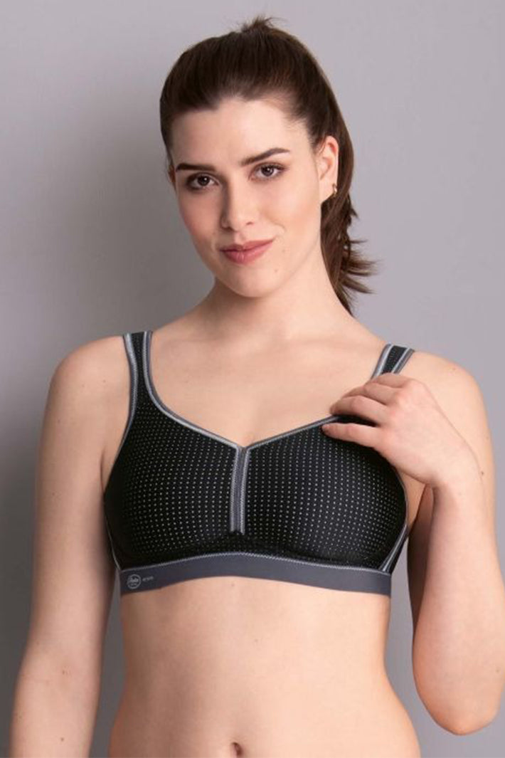 Woman wearing a black and gray bra against a plain background