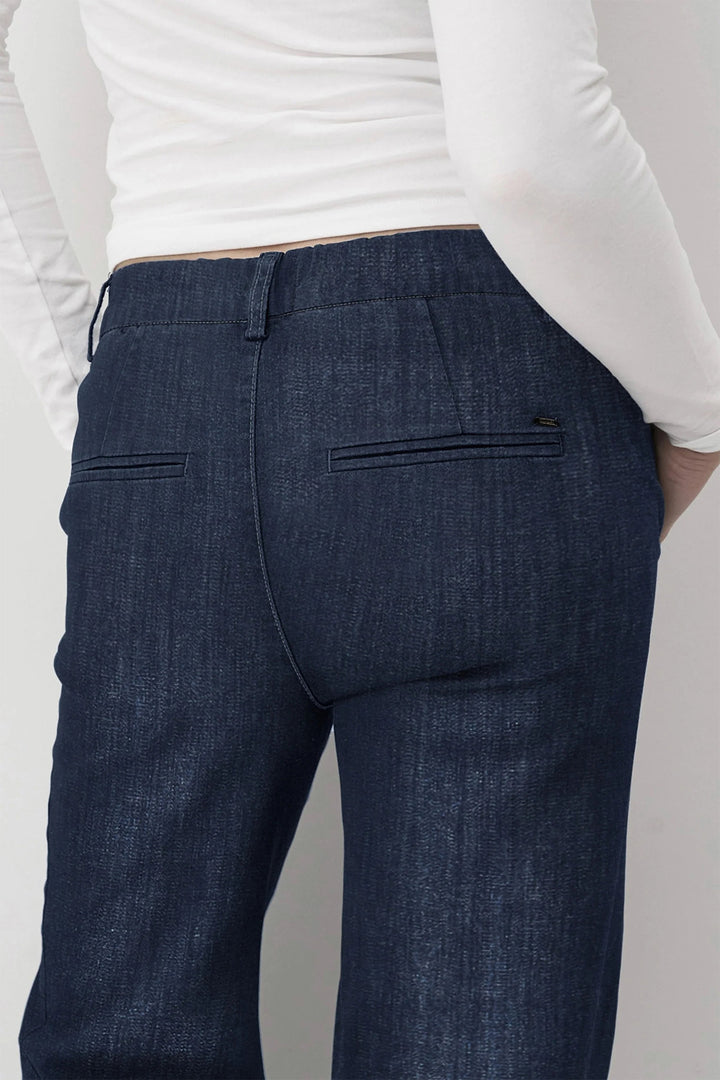 Person wearing blue pants with a white shirt on a plain background