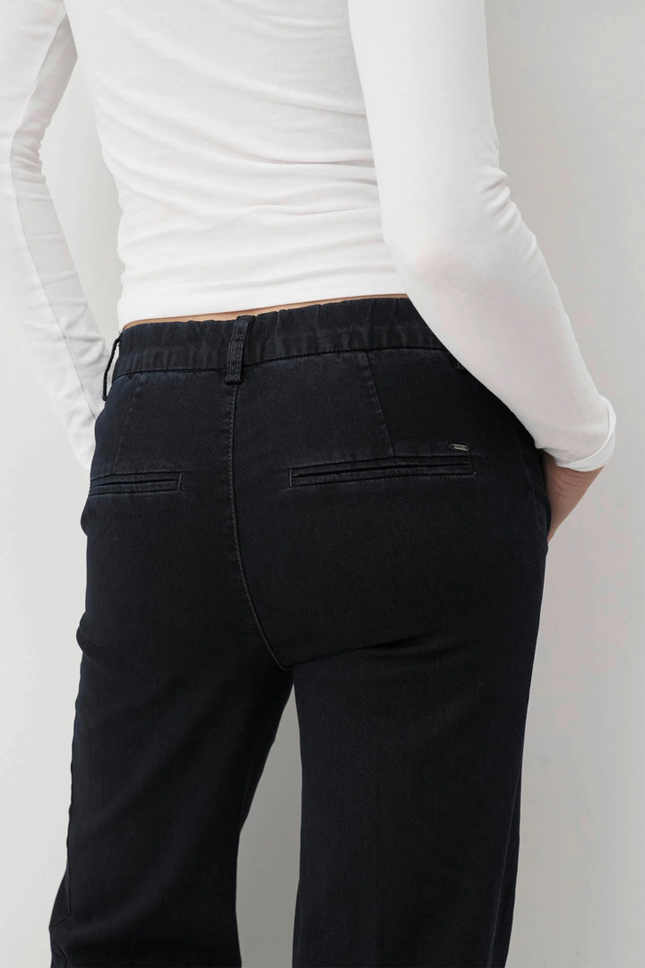 Person wearing navy pants and a white long-sleeve shirt against a plain background