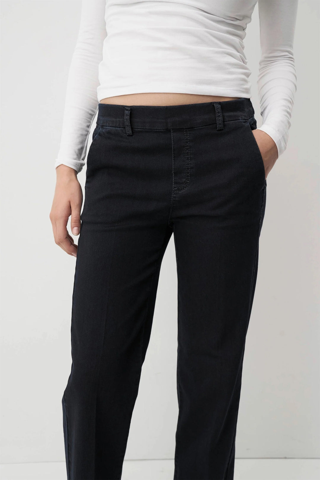 Person wearing navy pants and a white long-sleeve top on a white background