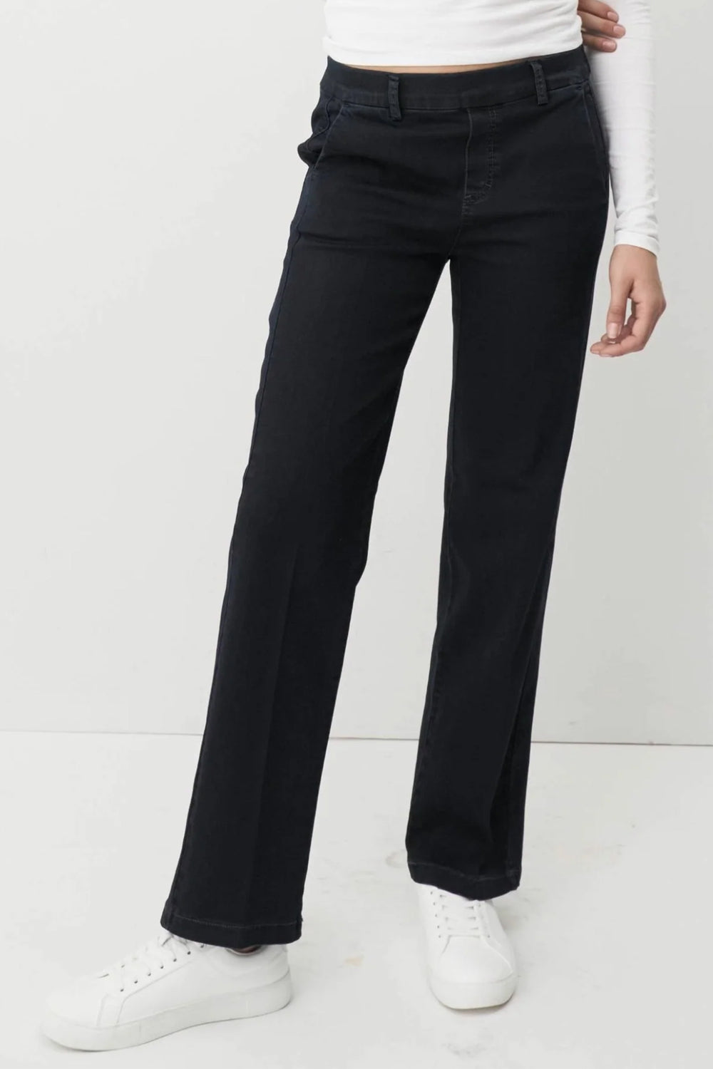 Person wearing navy pants and white shoes on a white background