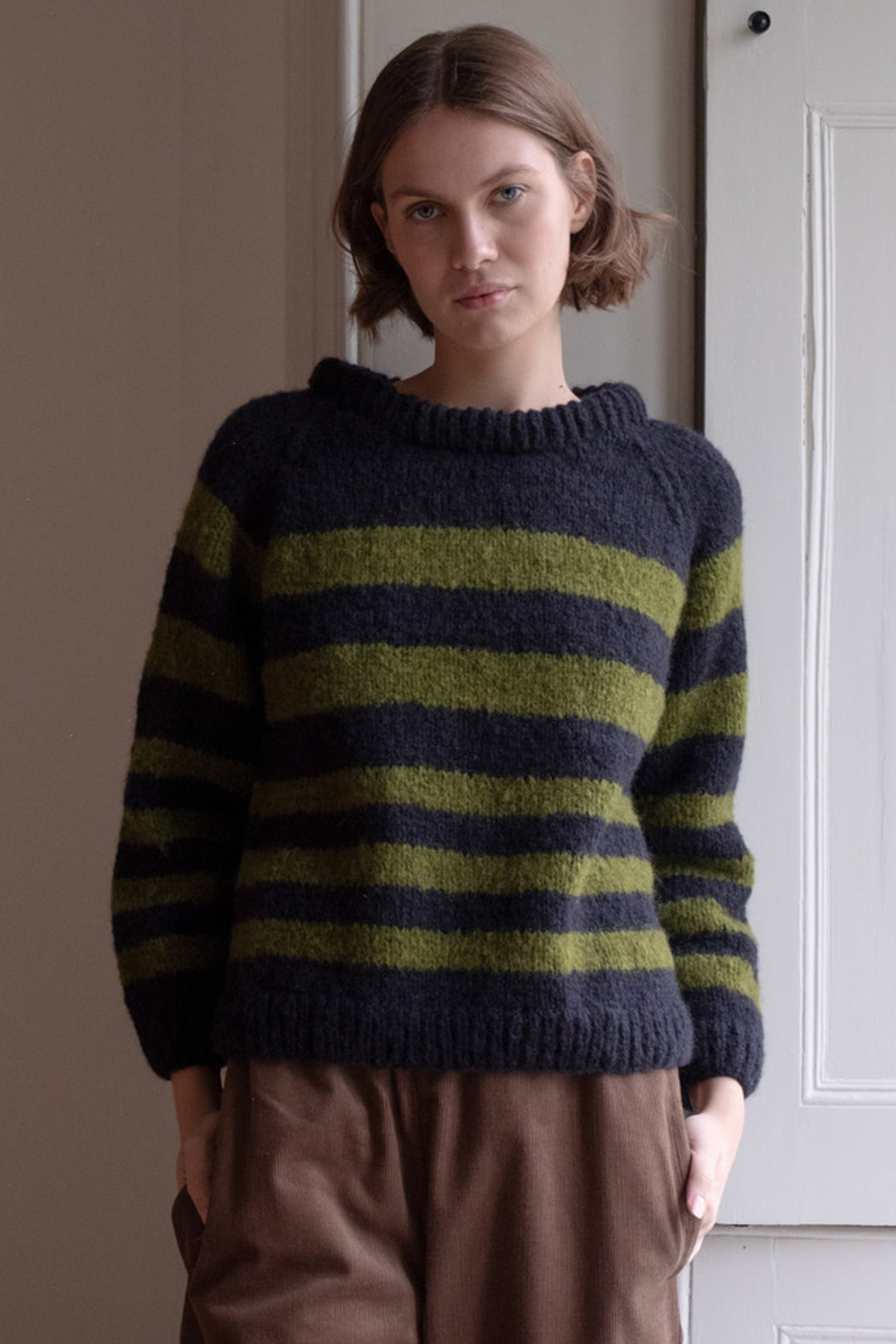 Person wearing a striped sweater standing against a neutral background