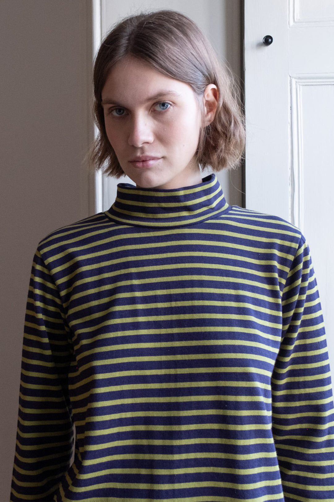 Person wearing a blue and yellow striped turtleneck sweater indoors.