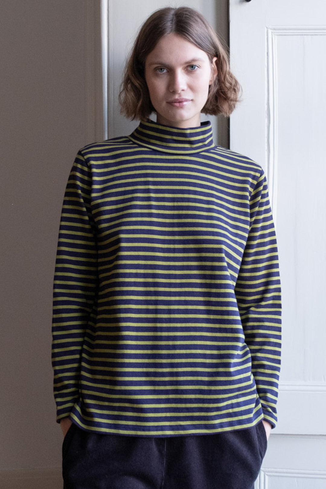 Person wearing a striped turtleneck sweater standing indoors.