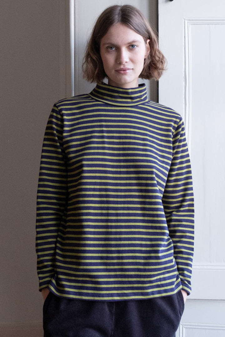 Person wearing a striped turtleneck sweater standing indoors.