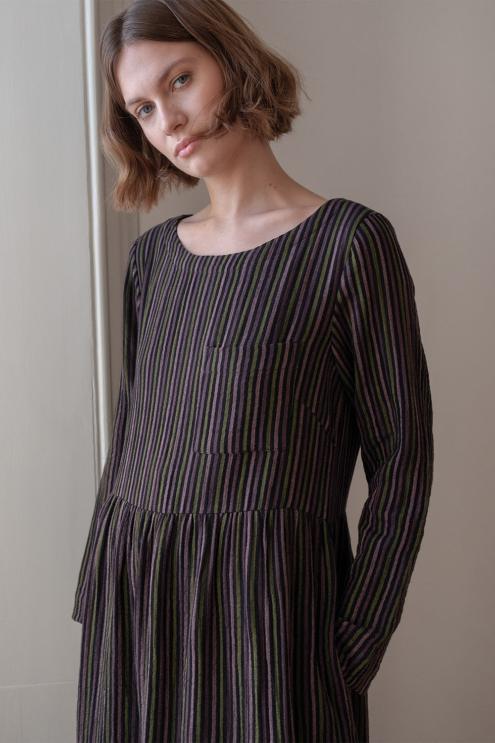 Woman wearing a black and white striped dress against a neutral background