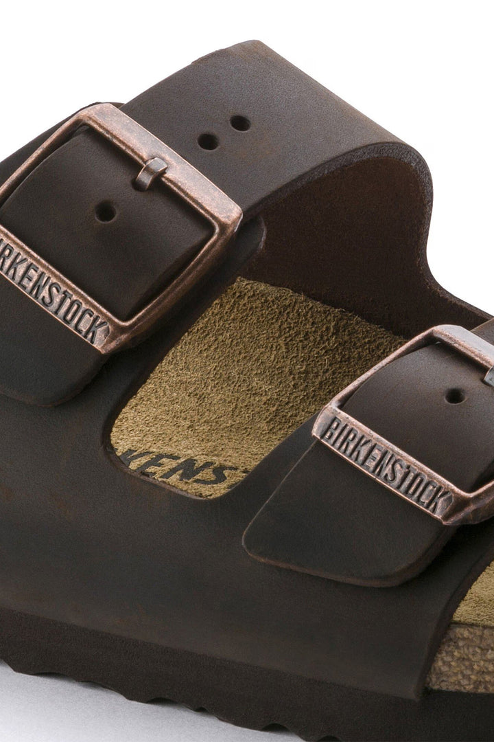 Close-up of a brown Birkenstock sandal with leather straps and buckle.