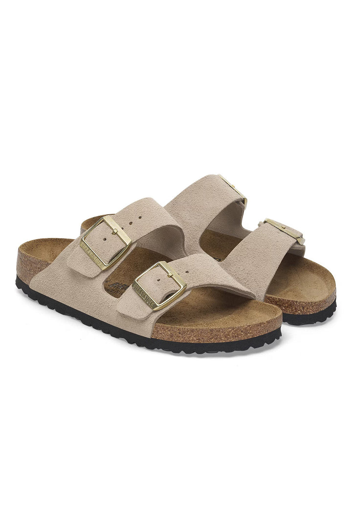 Pair of beige sandals with gold buckles on a white background
