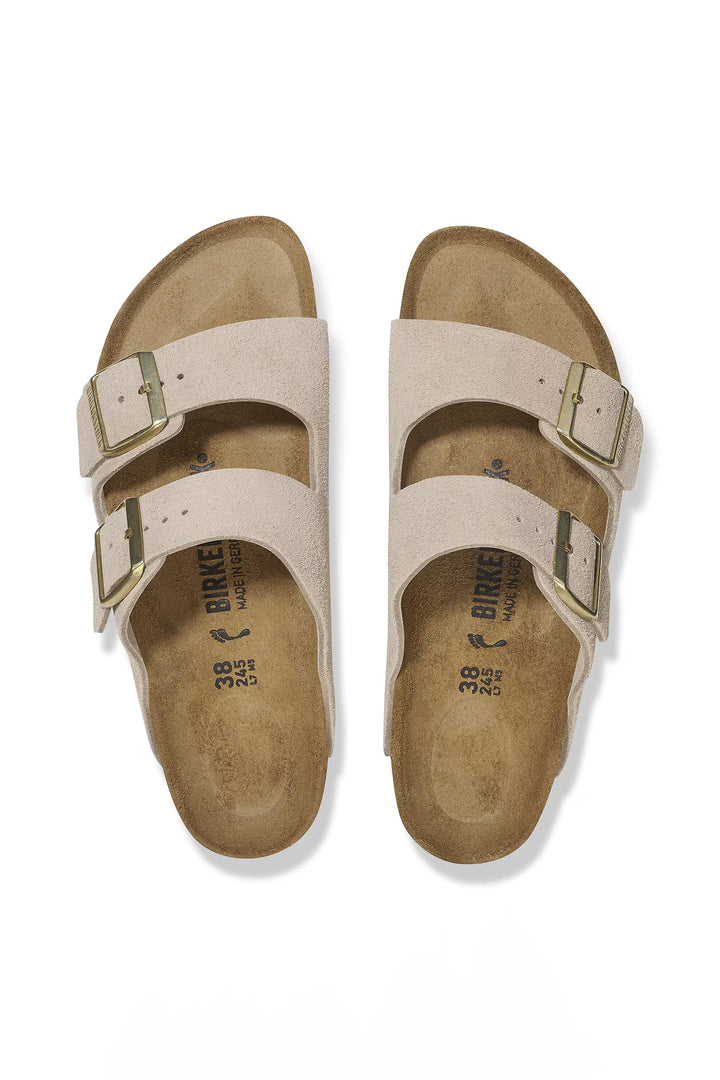 Pair of beige sandals with 'Birkenstock' branding on a white background