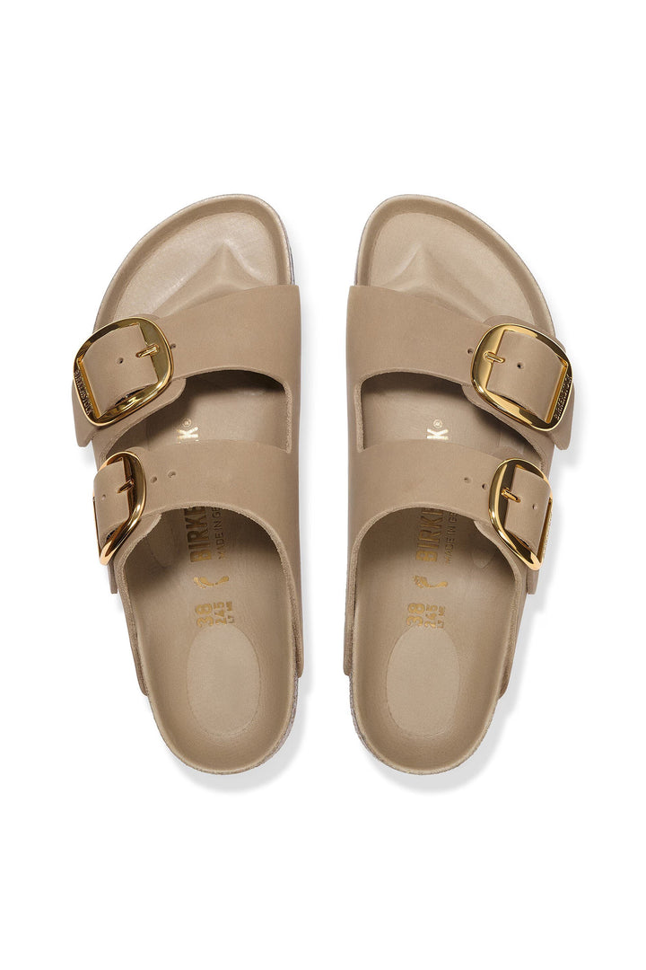 Pair of beige sandals with gold buckles on a white background