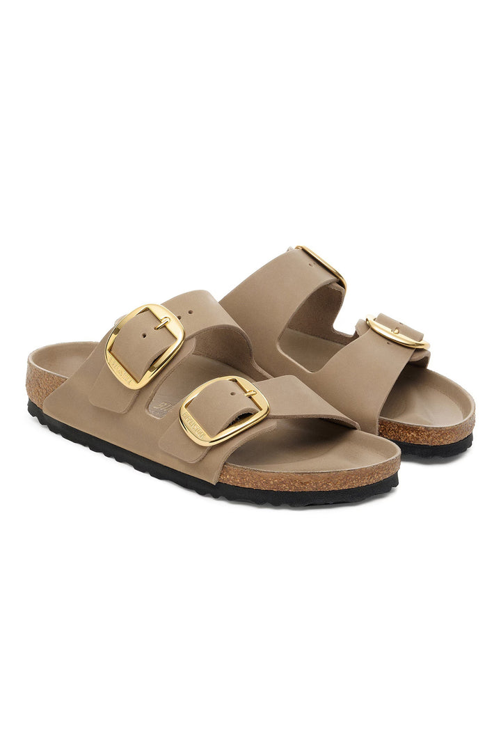 Pair of beige sandals with gold buckles on a white background