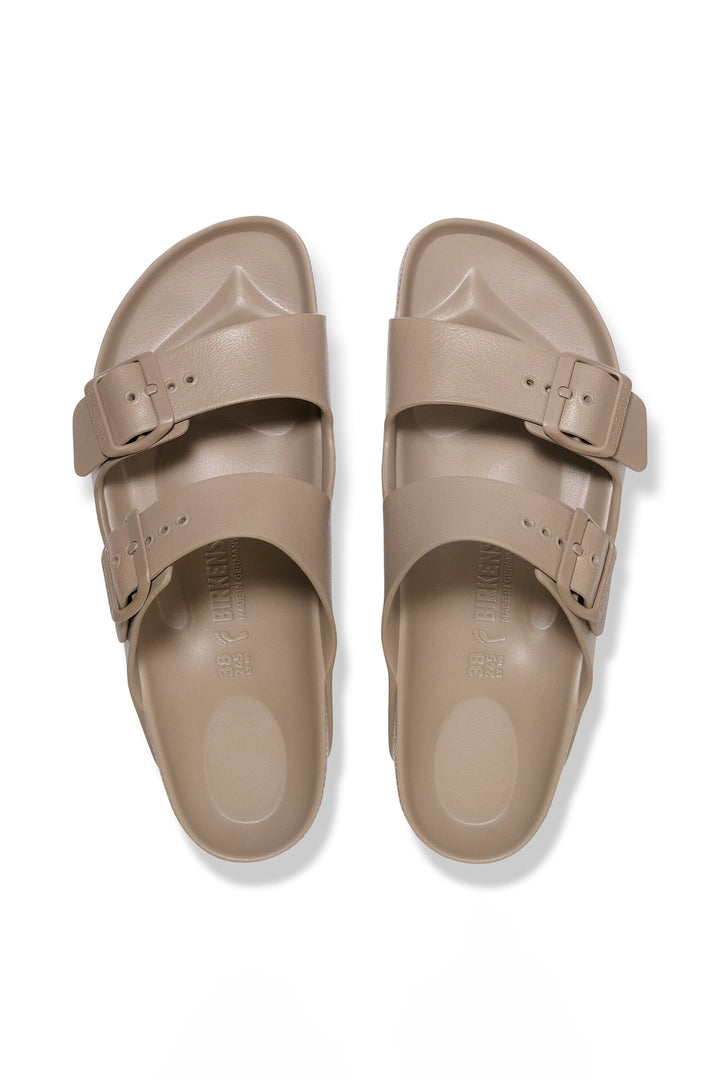 Pair of beige sandals with buckles on a white background