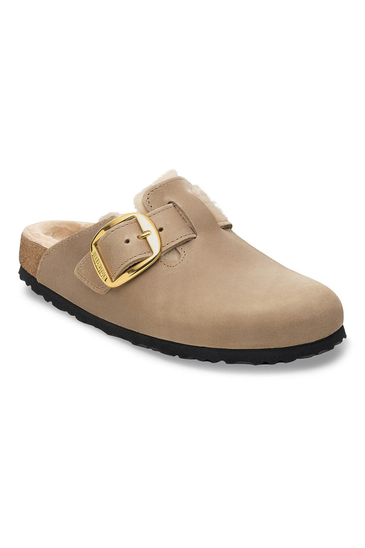 Beige clog shoe with gold buckle on a white background