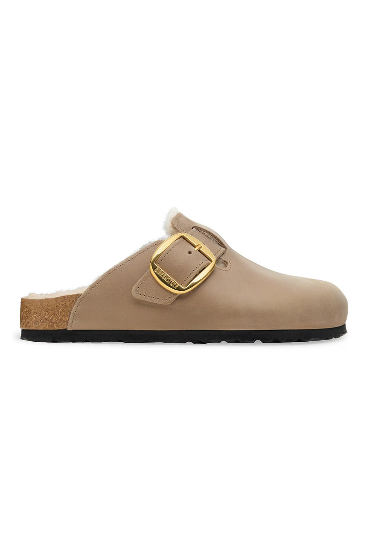 Beige clog shoe with a gold buckle on a white background