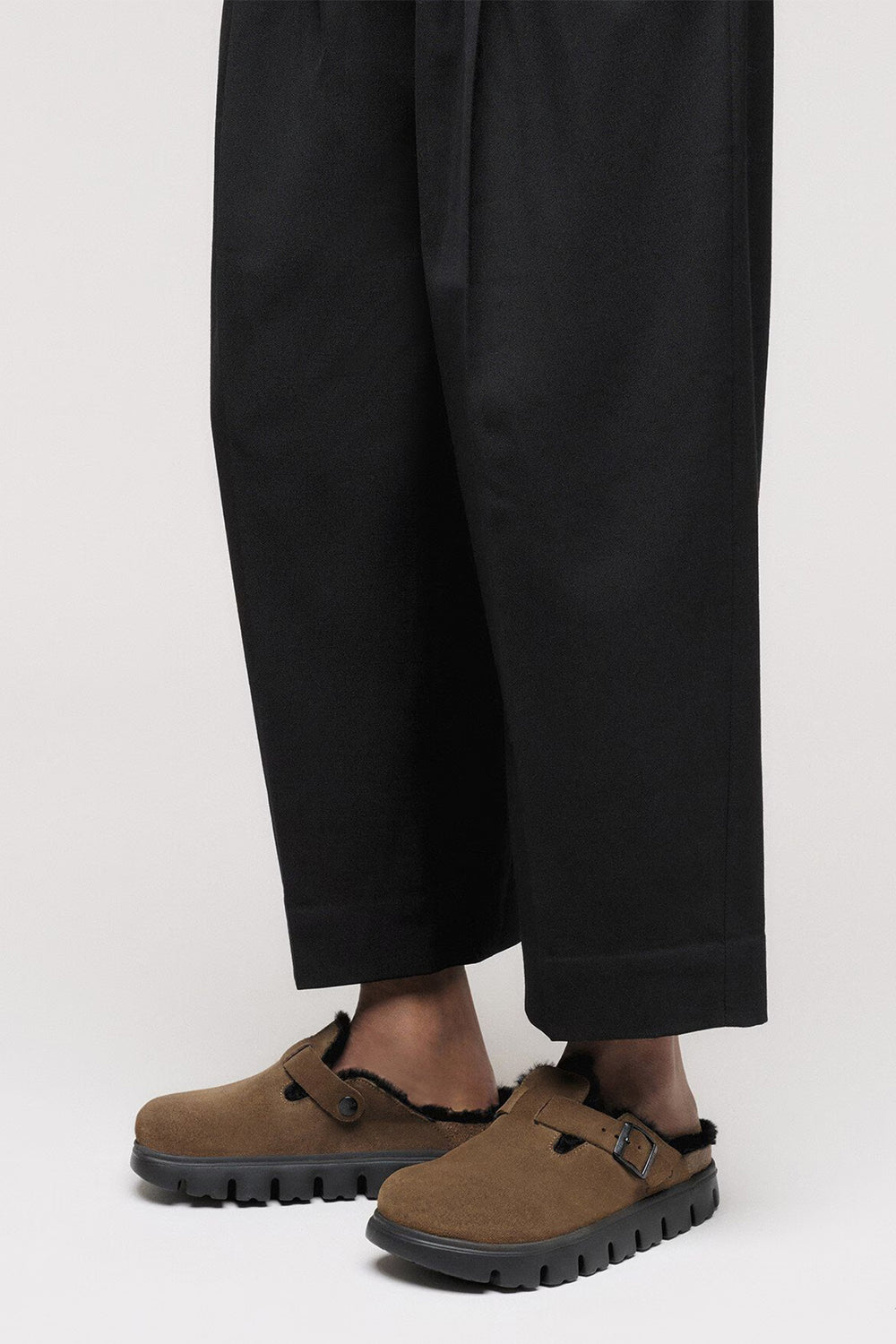 Brown shoes worn with black pants on a white background
