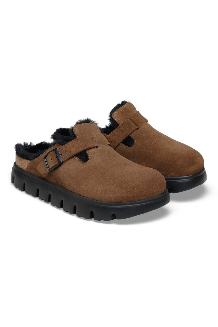 Pair of brown suede shoes with black soles and fur lining on a white background