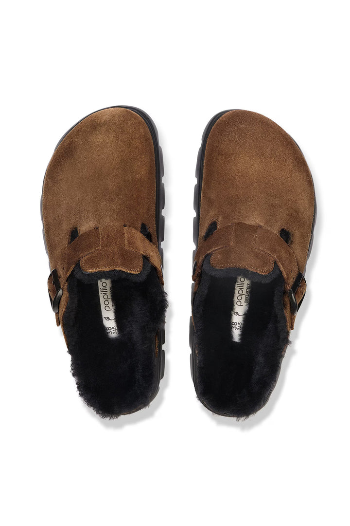 Pair of brown suede shoes with black fur lining on a white background