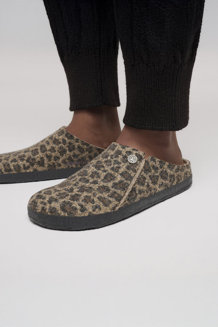 Leopard print slippers worn with black pants on a white background