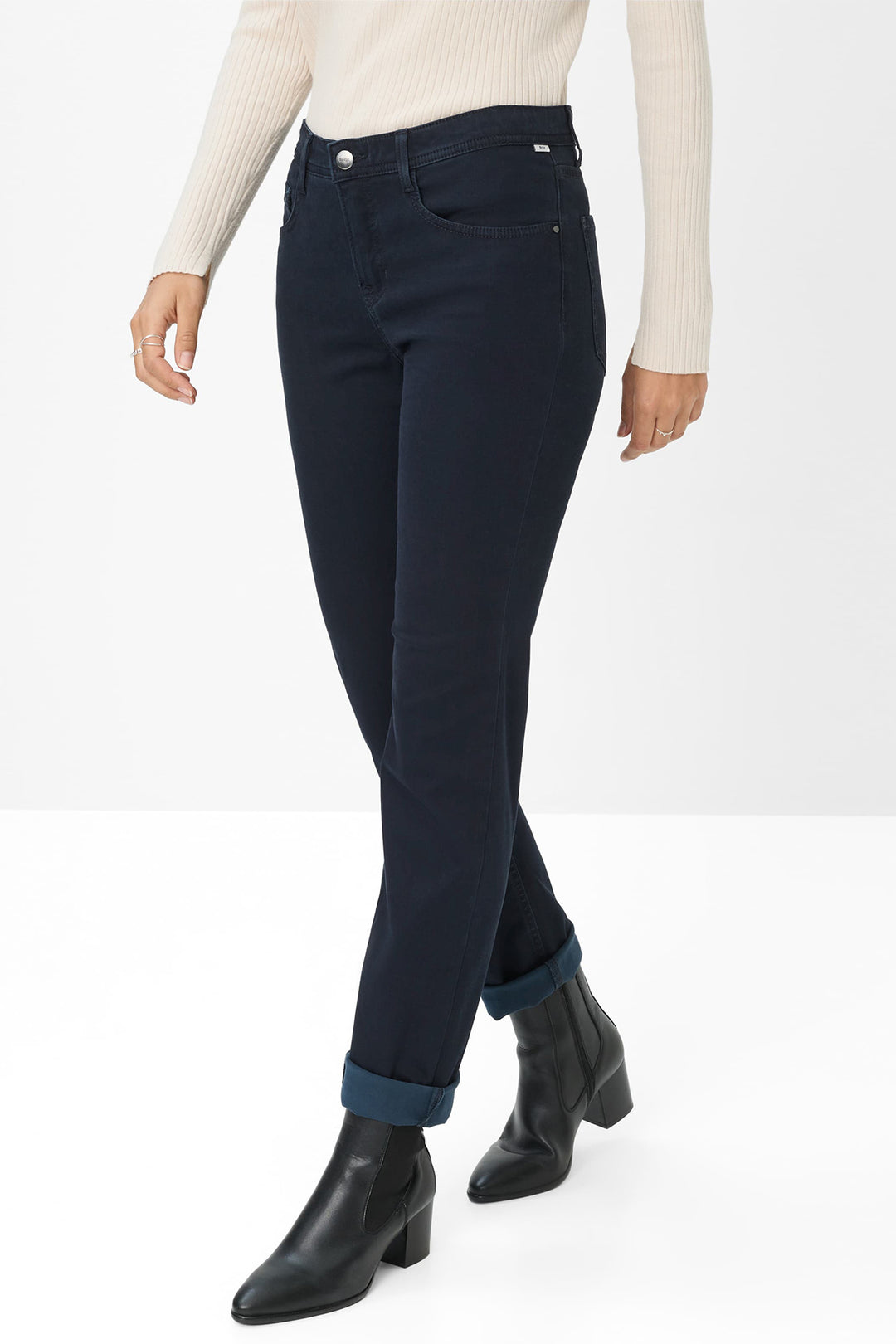 Person wearing navy jeans and black boots on a white background