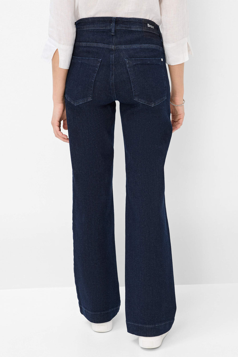 Person wearing dark blue jeans on a white background