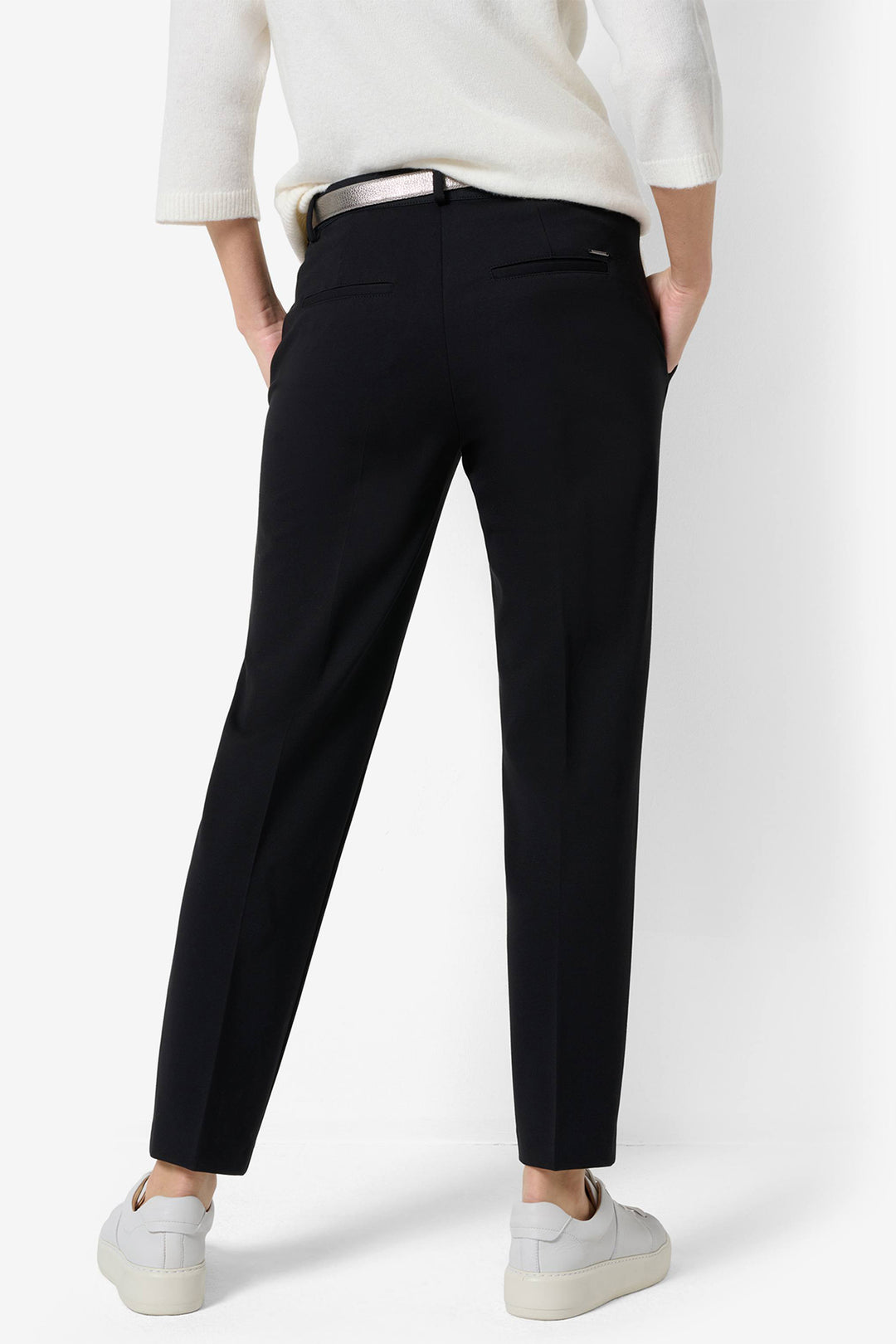 Person wearing black pants and a white top on a white background