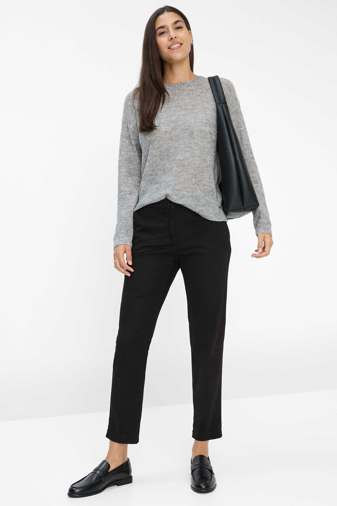 Woman wearing a gray sweater and black pants on a white background