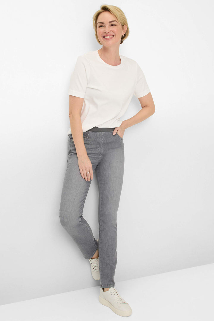 Woman wearing a white t-shirt and gray jeans against a white background