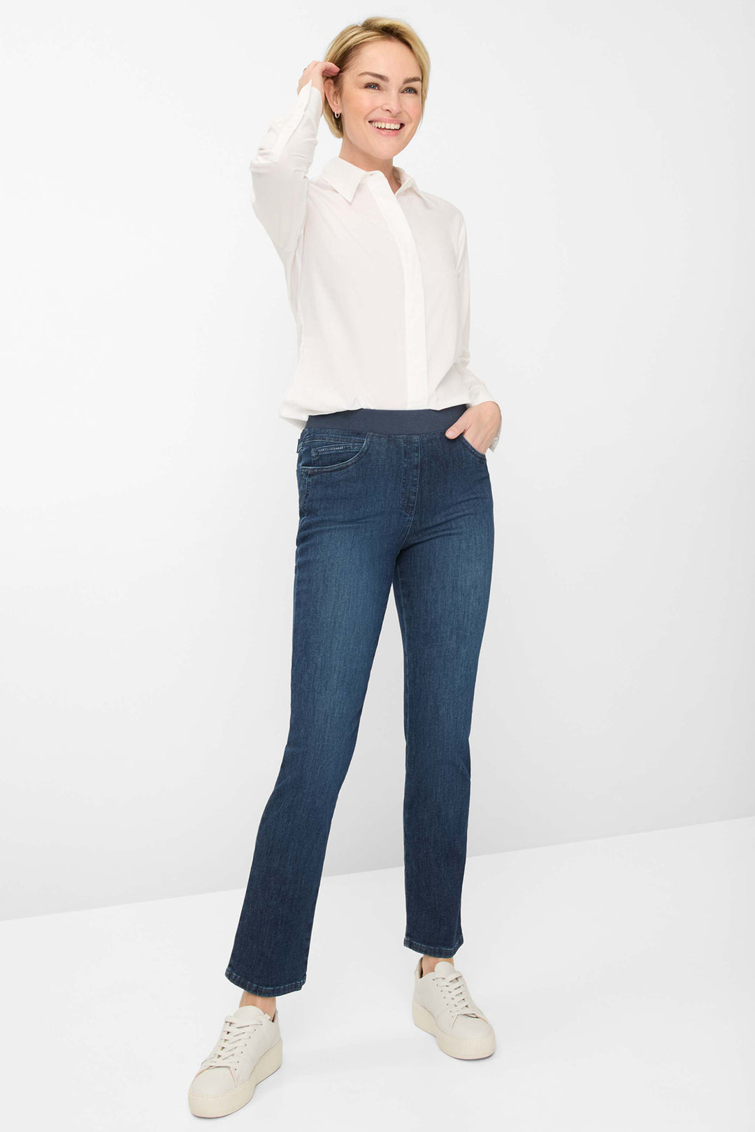 Woman wearing a white shirt and blue jeans on a white background