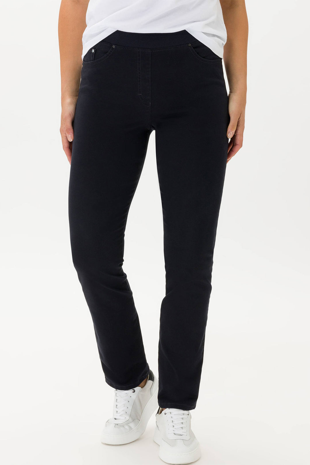 Person wearing black jeans and white sneakers on a white background