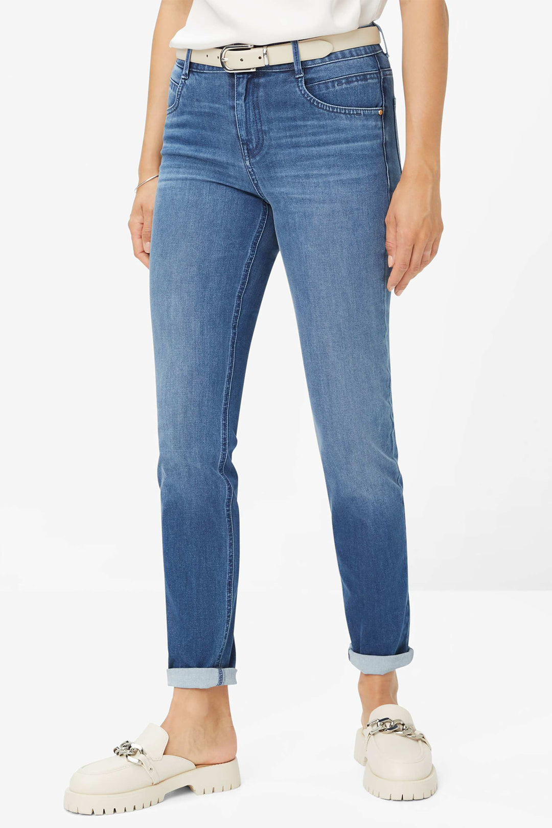 Person wearing blue jeans and white shoes on a white background