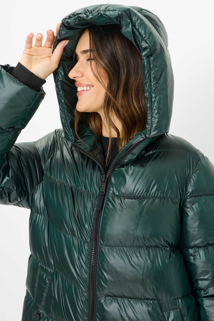 Woman wearing a green puffer jacket with a hood on a white background