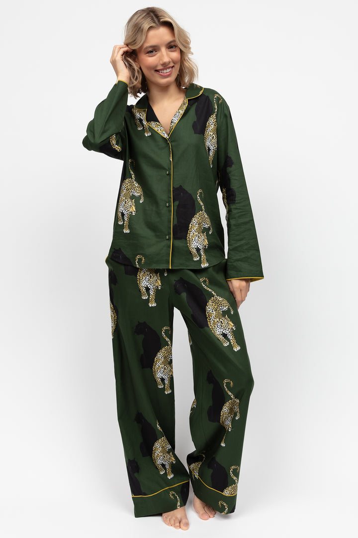 Woman wearing green pajama set with leopard print on a white background