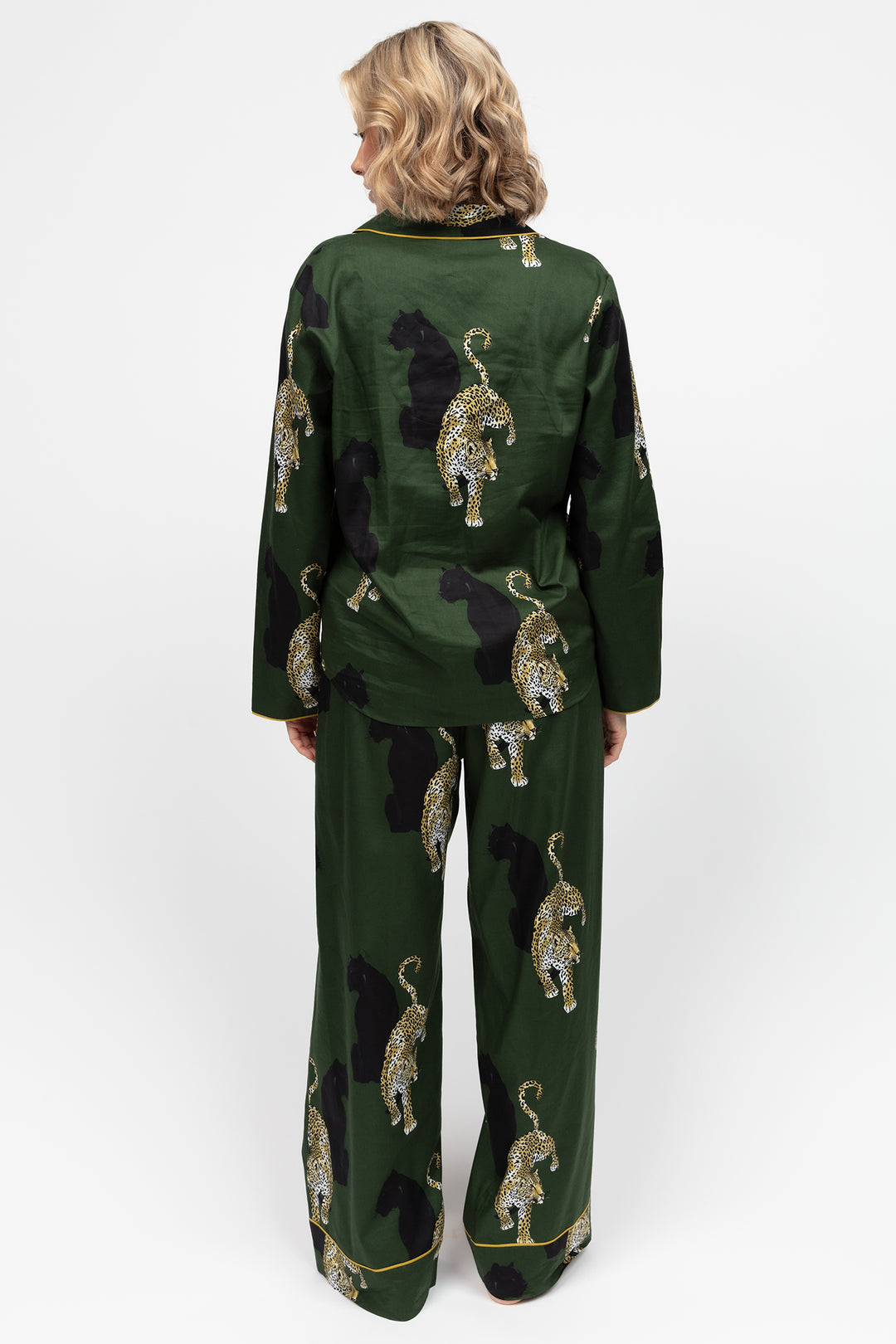 Person wearing a green outfit with embroidered animal patterns on a white background