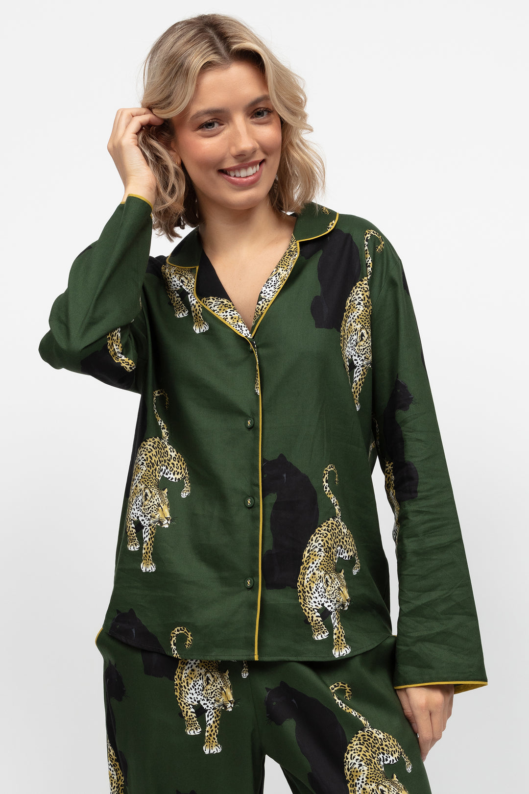 Woman wearing a green pajama set with leopard print on a white background