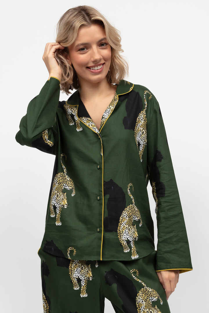 Woman wearing a green pajama set with leopard print on a white background