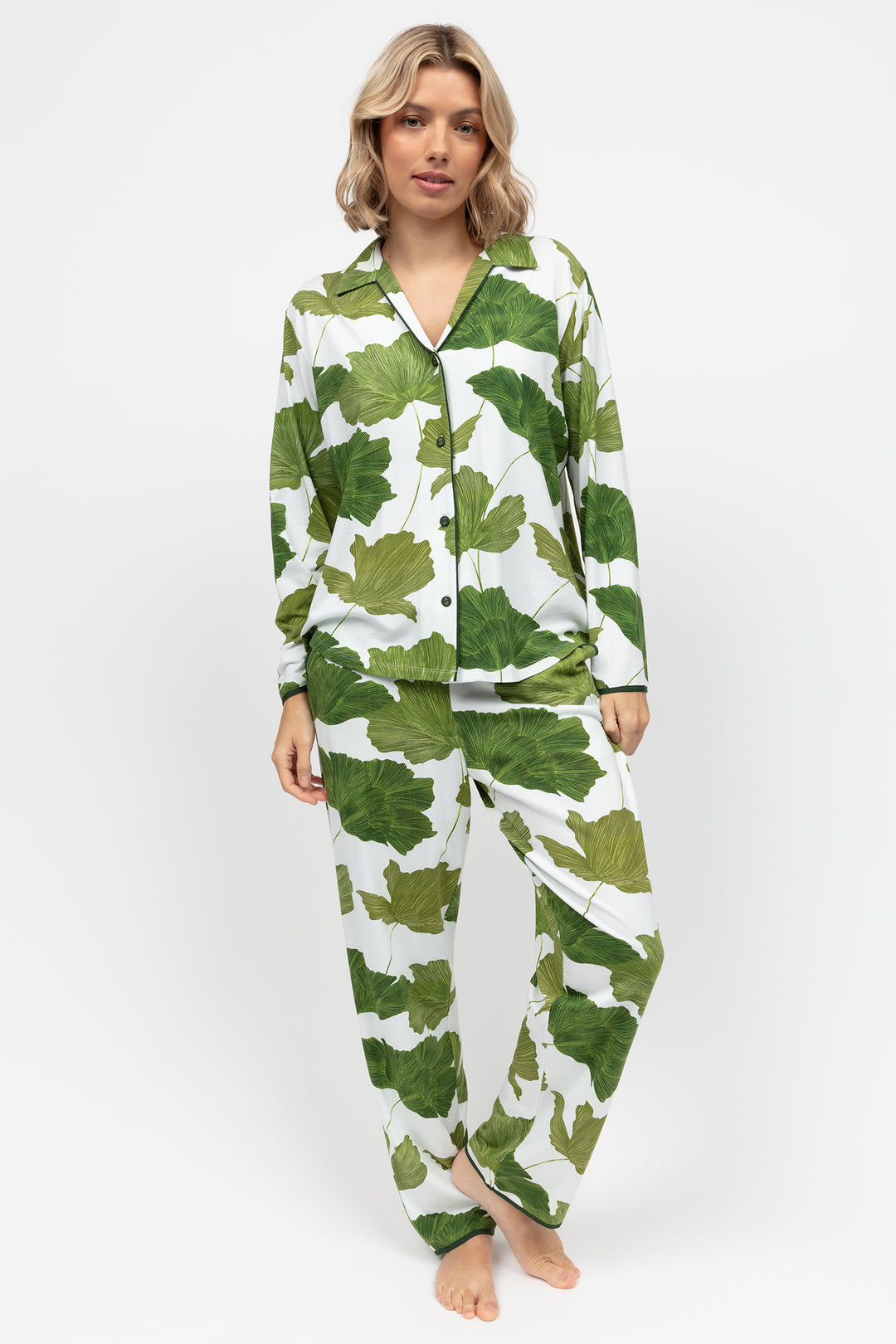 Woman wearing green and white leaf-patterned pajamas on a white background