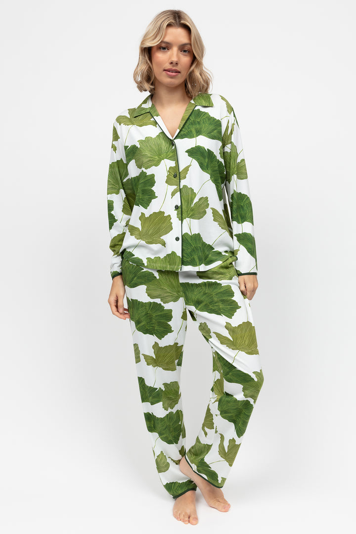 Woman wearing green and white leaf-patterned pajamas on a white background