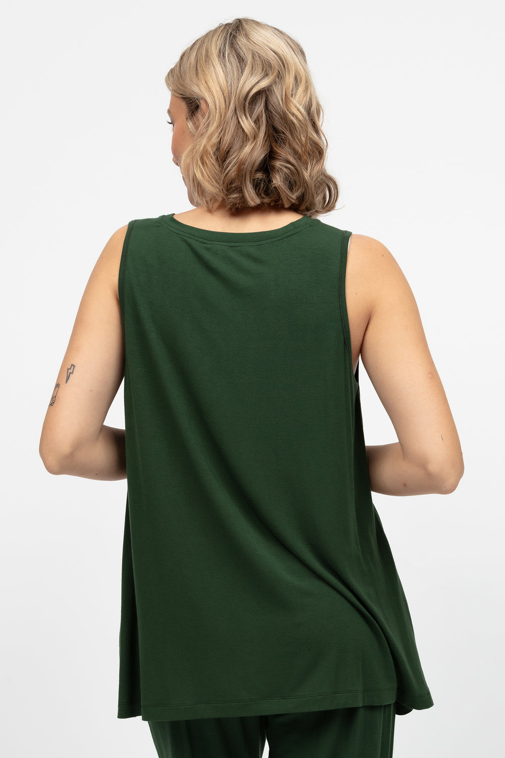Woman wearing a green sleeveless top and pants on a white background