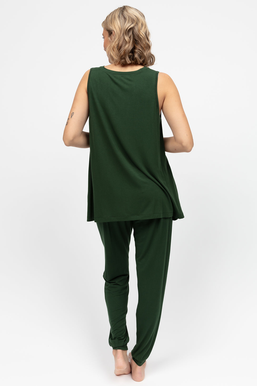 Woman wearing a green sleeveless top and pants on a white background