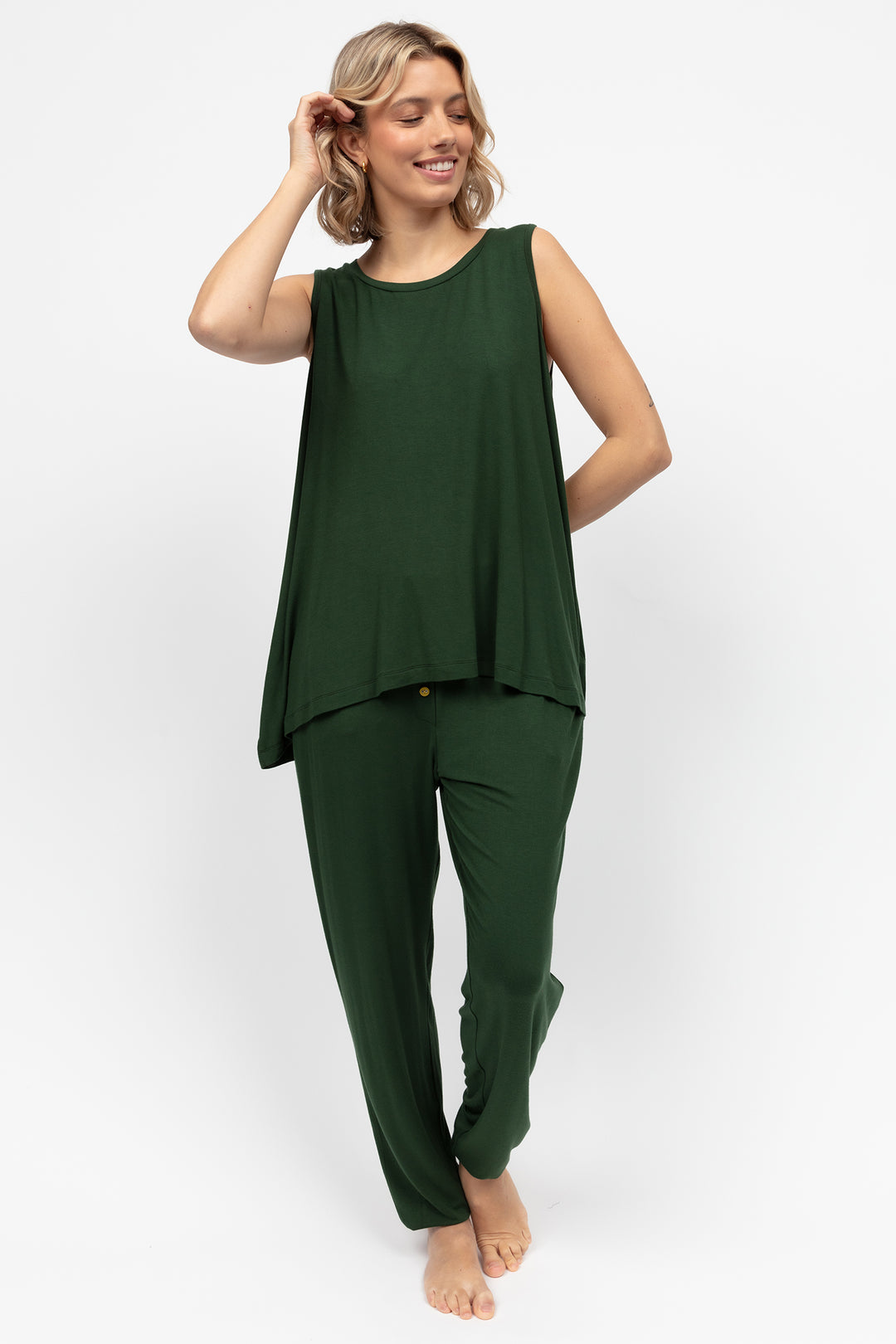 Woman wearing a green sleeveless top and pants on a white background