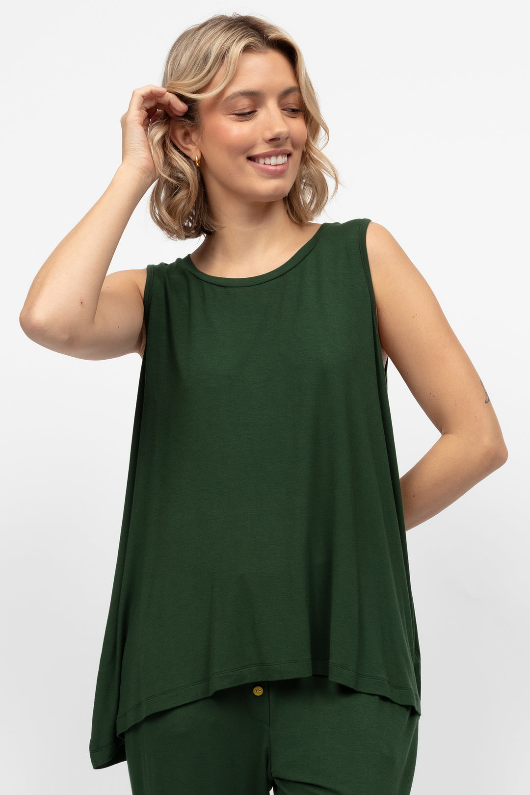 Woman wearing a green sleeveless top and pants on a white background